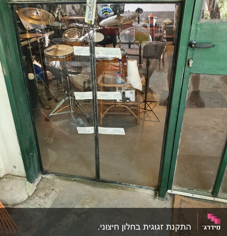 דלת זכוכית עם תופים וכלי נגינה מאחוריה